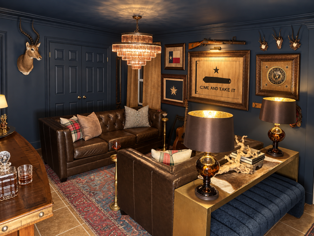 Moody navy downstairs lounge with leather seating and collected art